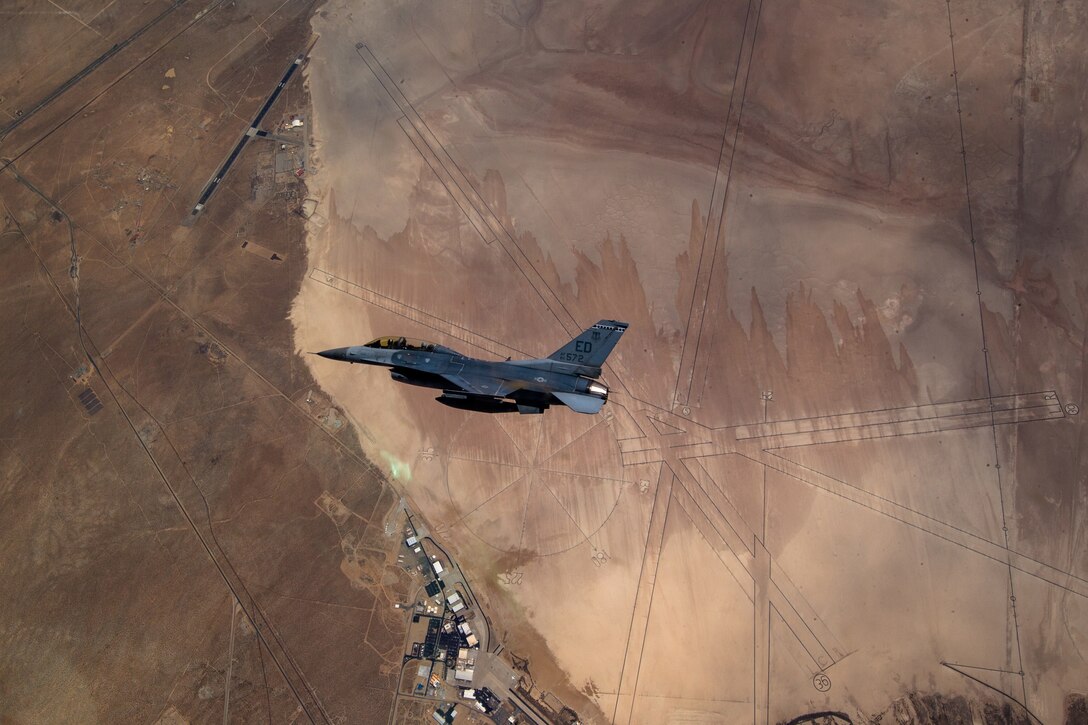 A military jet flies above an Air Force base.