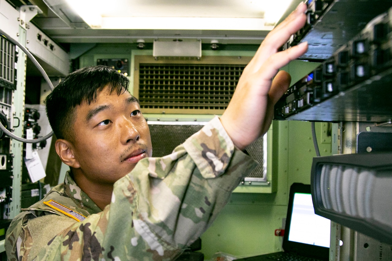 A soldier works on computer equipment.