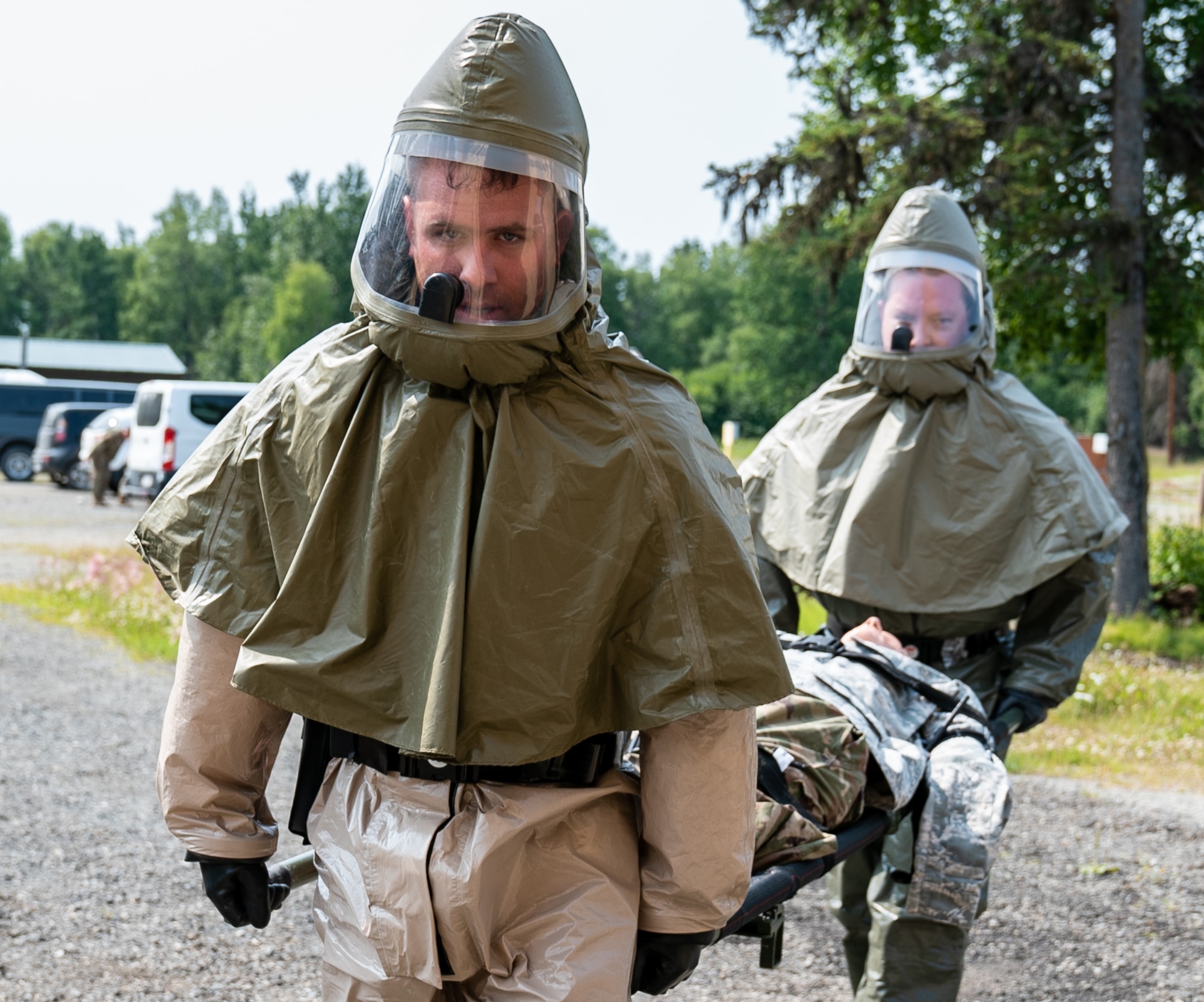 Airmen carry a mannequin into a training decontamination area.