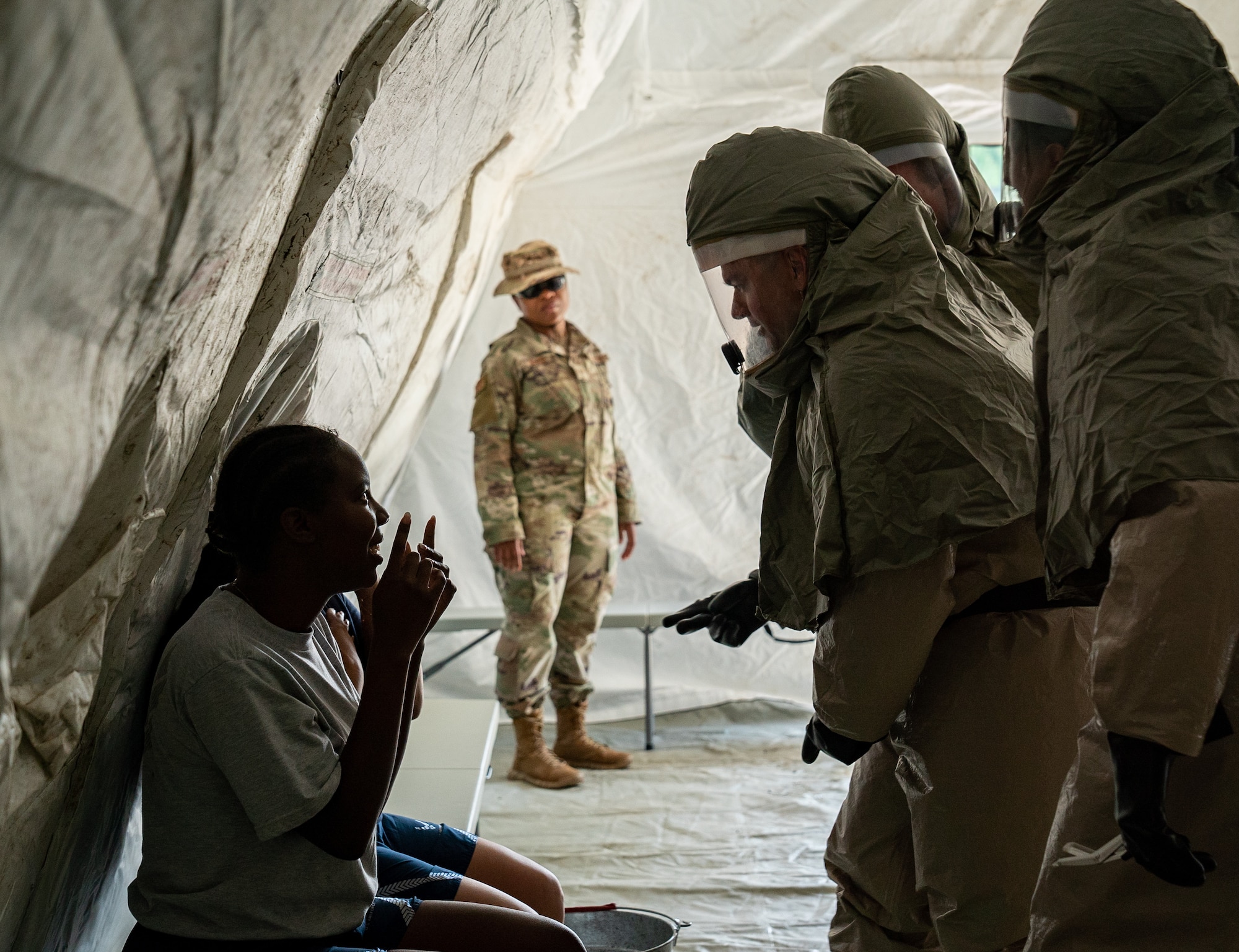 Airmen determine the severity of a patient’s simulated injuries as an instructor observes during a decontamination training exercise.