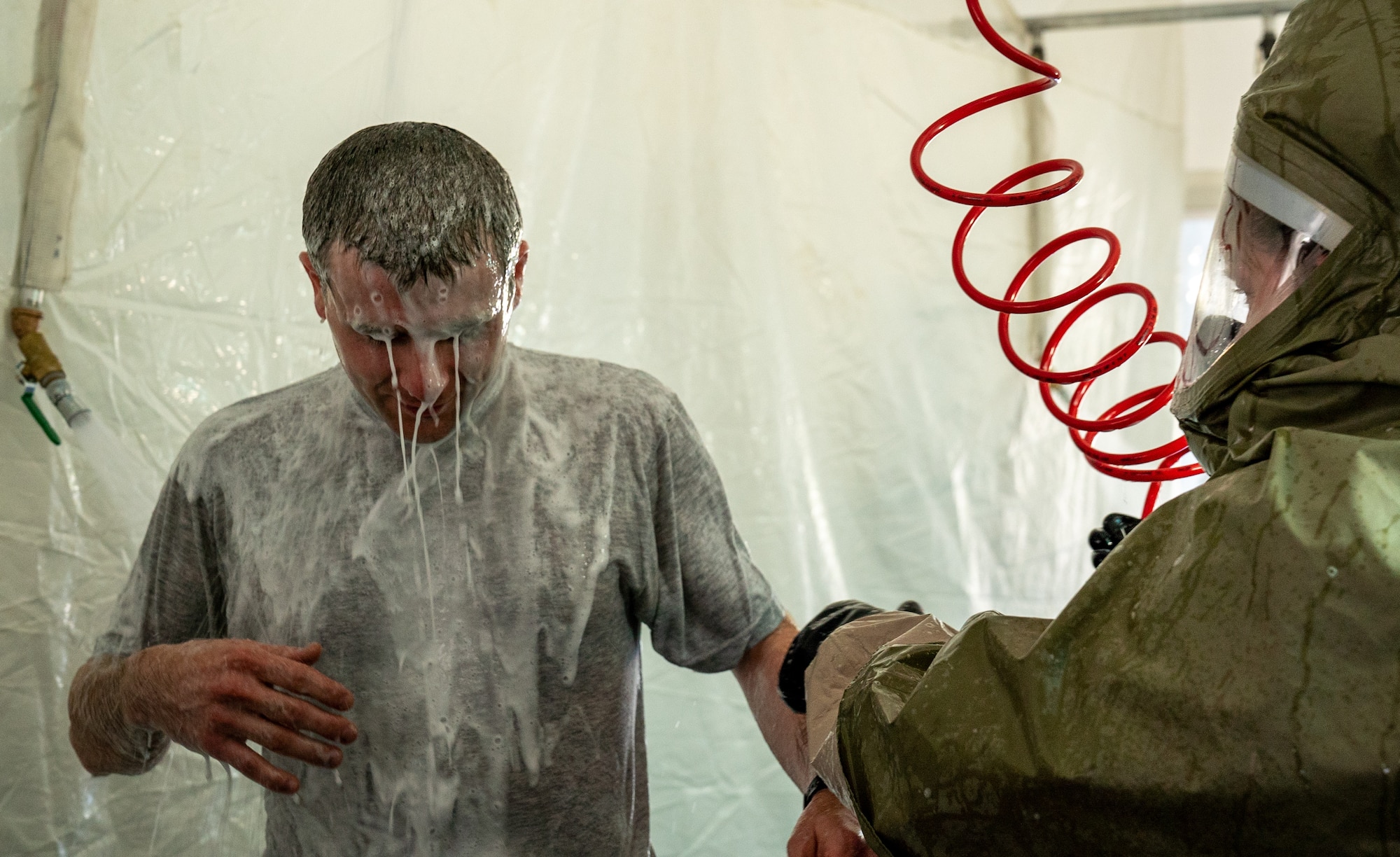 A U.S. Airman is taken through a decontamination shower during a training exercise.