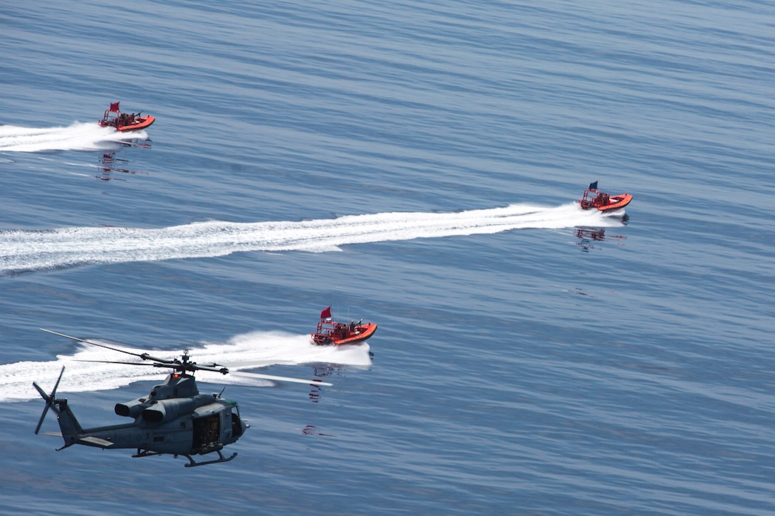 A helicopter flies over three small boats in a body of water.