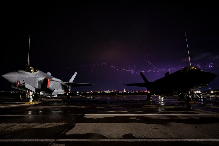 Two F-35 Lightning IIs sit on the flight line during thunderstorm,