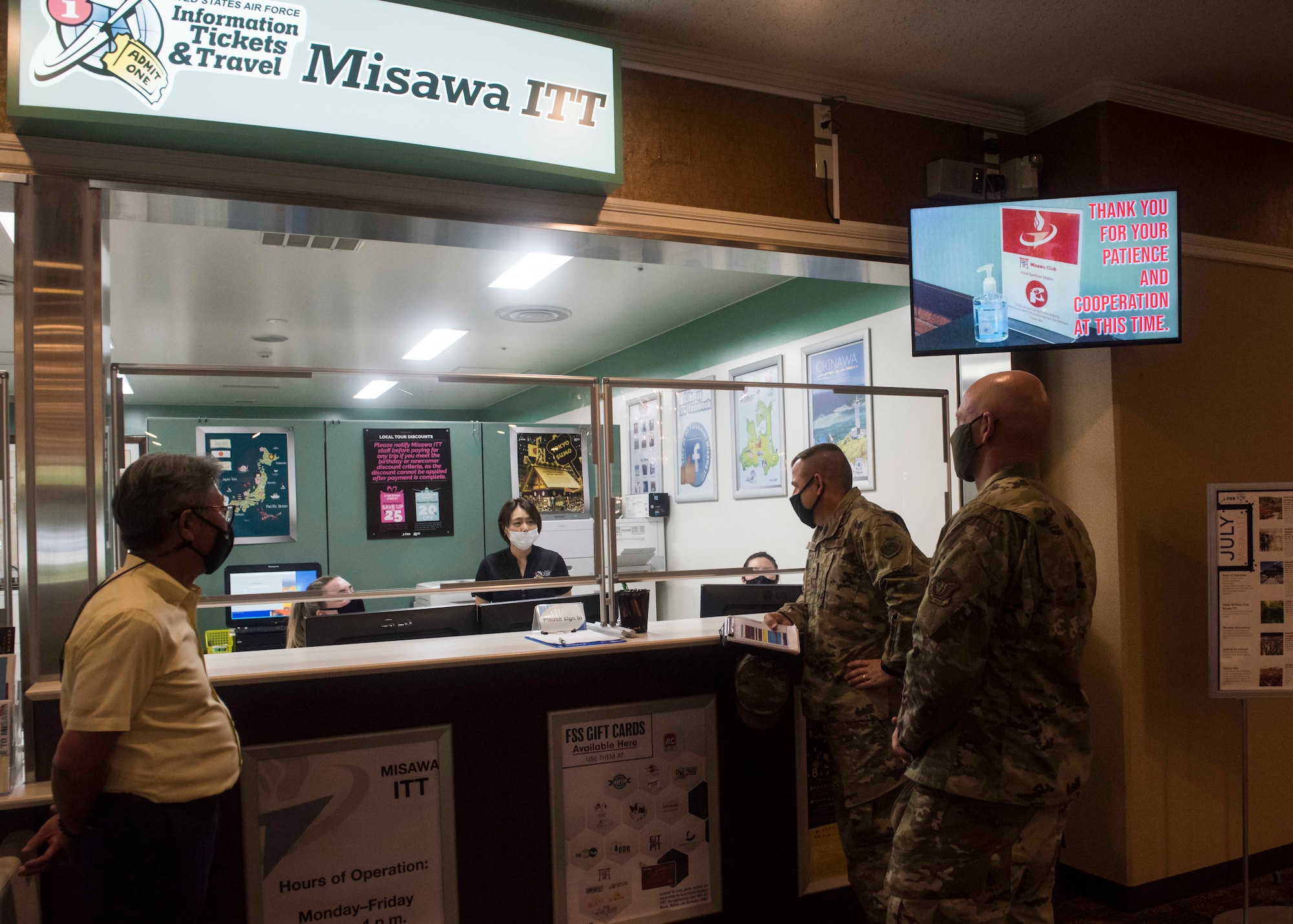 Service members and civilians talk to each other over a counter.