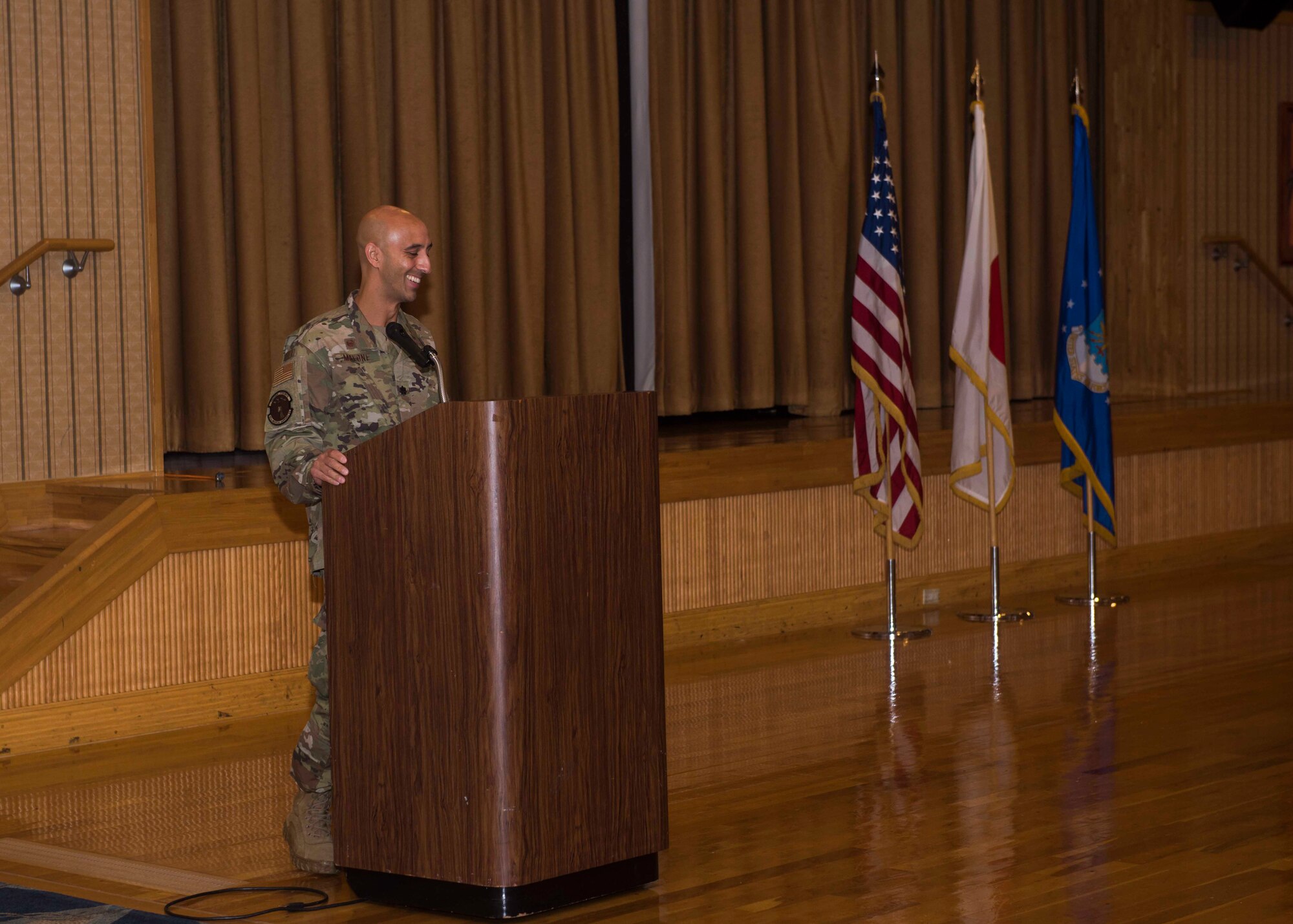 A service member talks while standing behind a podium.