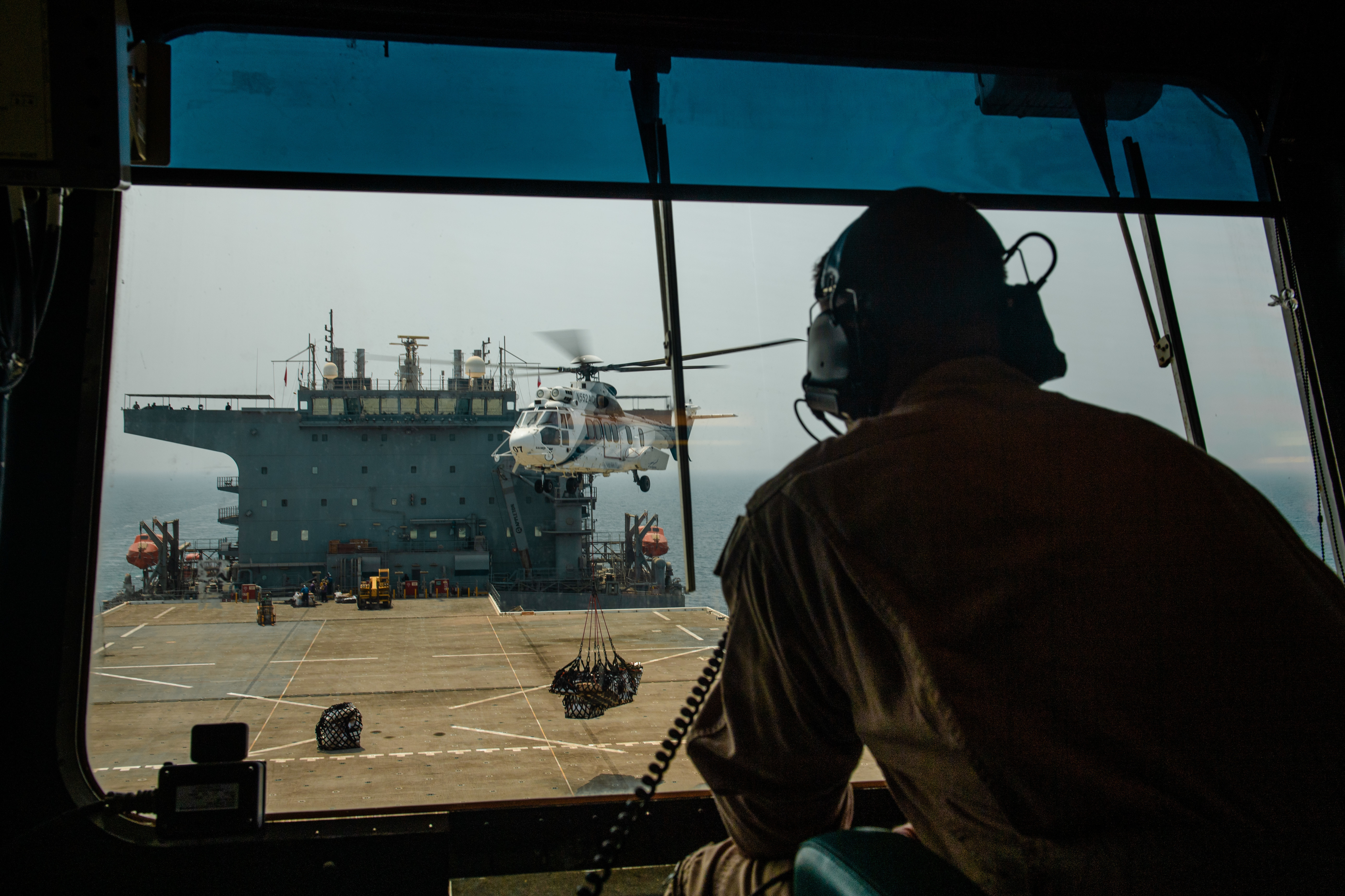 Lt. Nick Oberkrom watches an SA 330 puma helicopter transfer cargo to expeditionary sea base USS Lewis B. Puller (ESB 3) during a replenishment-at-sea in the Arabian Gulf.