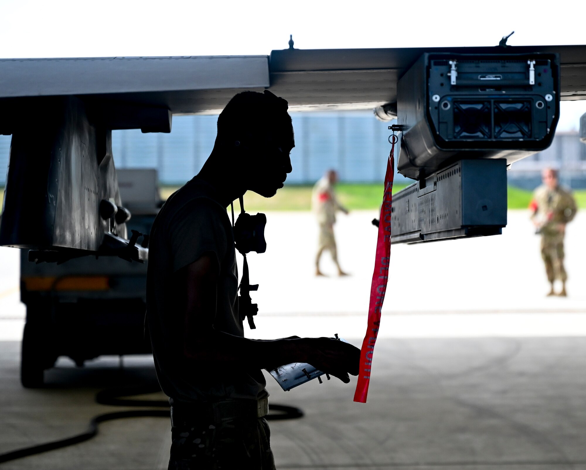 A silhouetted Airman works on an airplane.