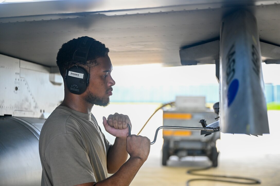 An Airman uses a tool on an F-16 Fighting Falcon airplane.