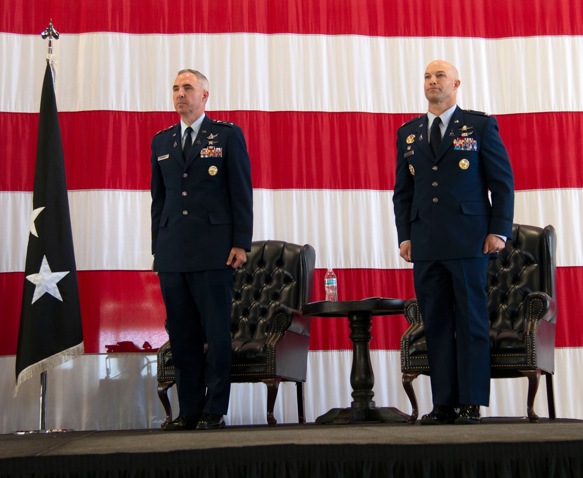 two men stand at attention on a stage