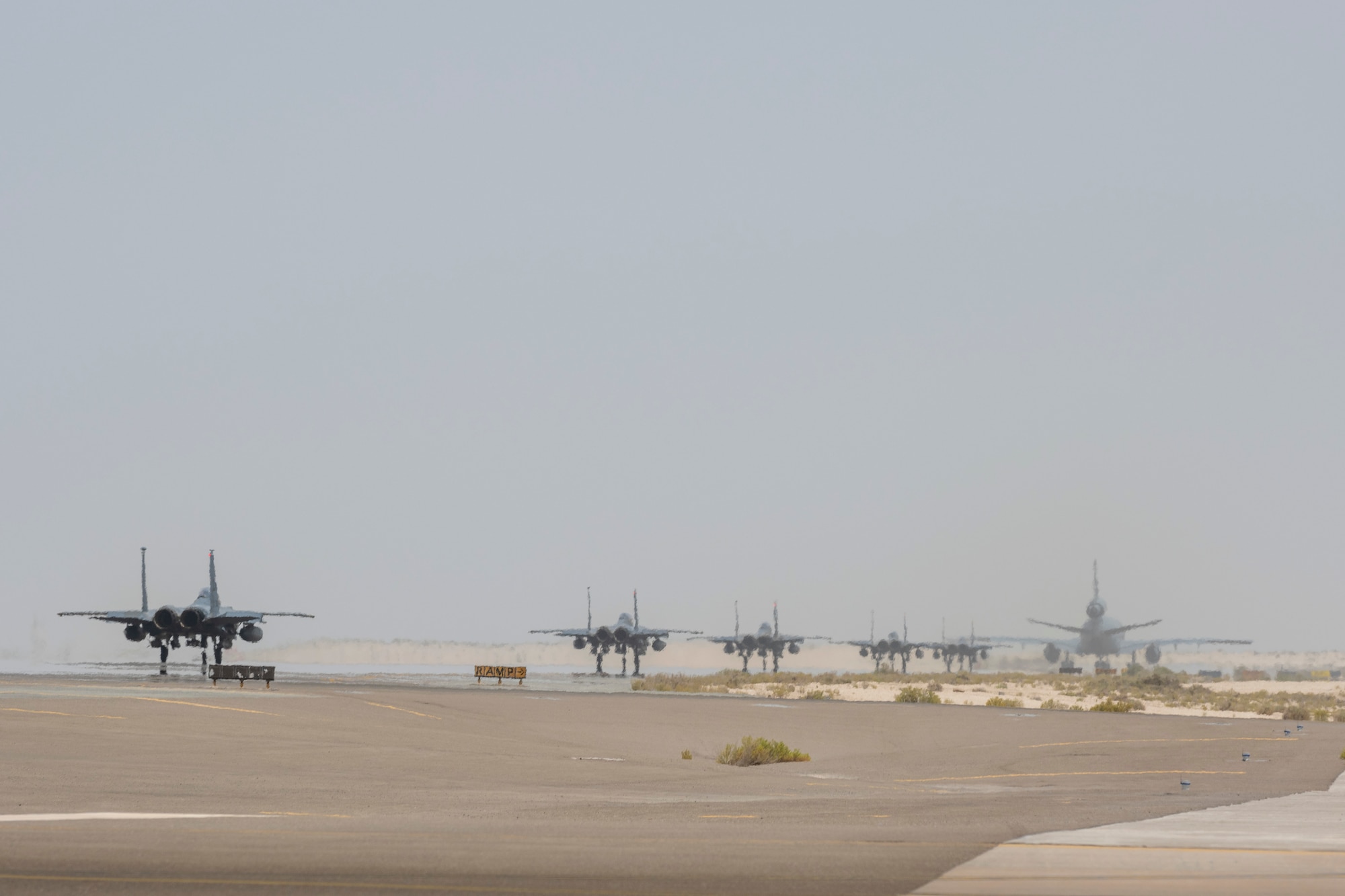 A KC-10 and 5 F-15s taxi down the runway