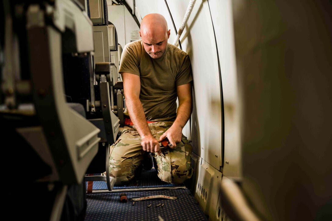 Airman works on flooring of aircraft cabin