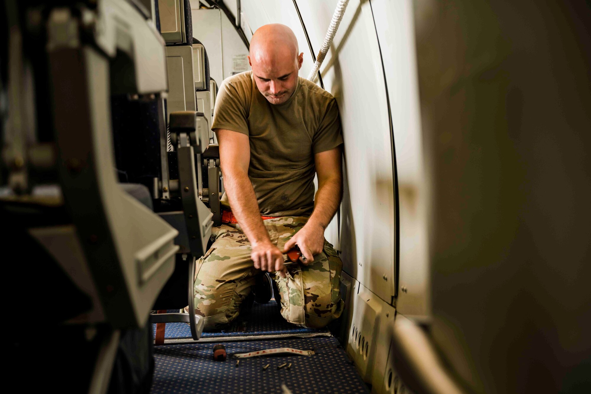 Airman works on flooring of aircraft cabin
