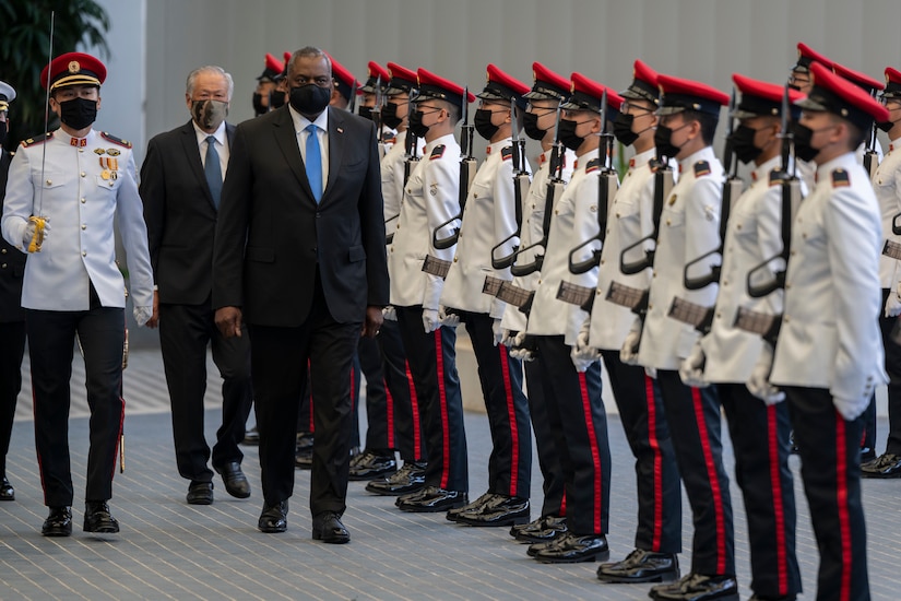 The US Secretary of Defense walks along a line of Singapore troops during a welcome ceremony.