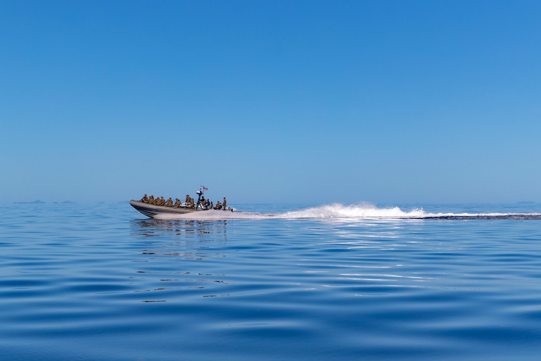 A group of sailors ride in a boat leaving a wake behind.