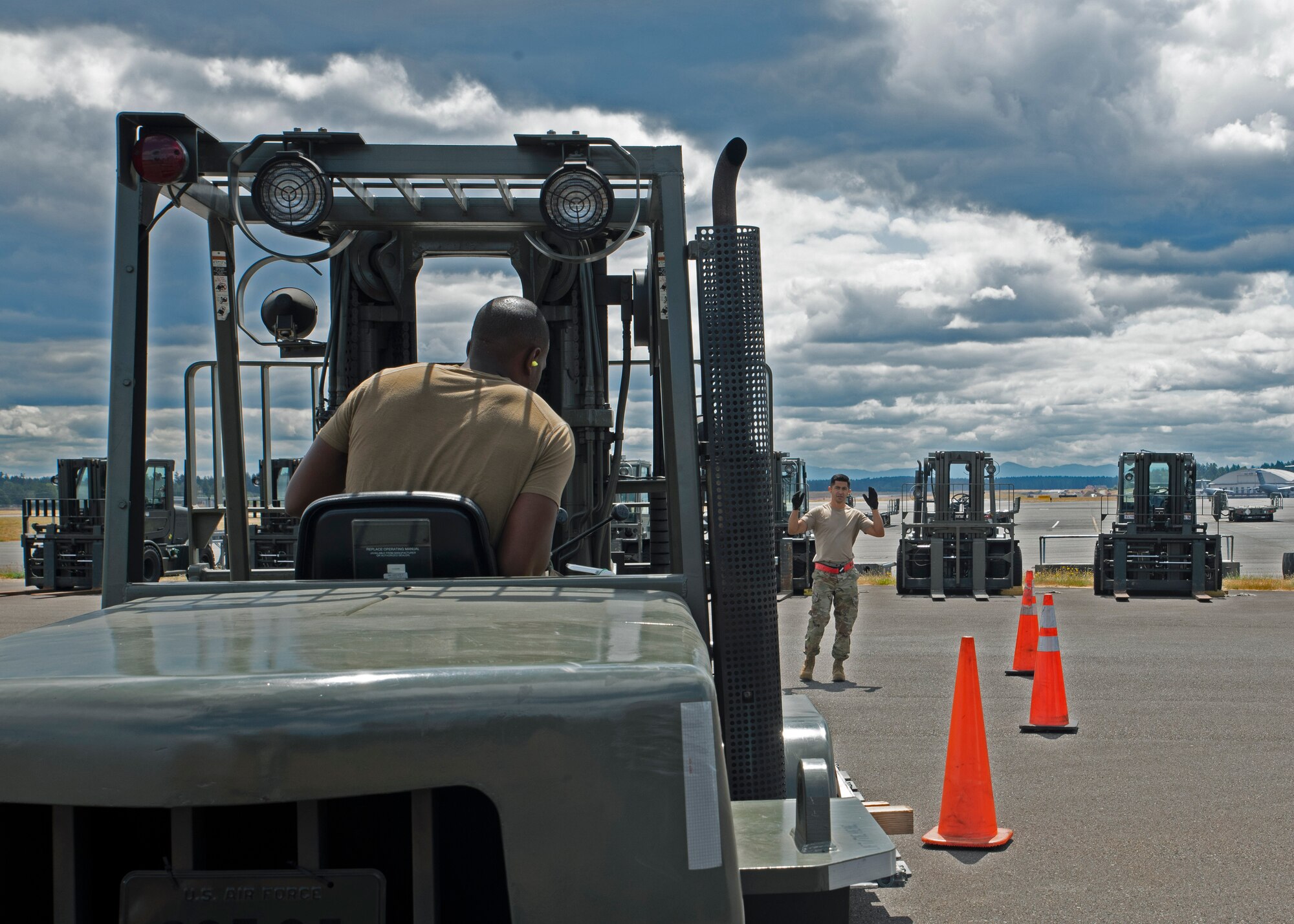(From left) U.S. Air Force Staff Sgt. Wesley Valentine, passenger service supervisor with the 62nd Aerial Port Squadron, watches the cues from U.S. Air Force Tech. Sgt. Emmanuel Escobar, 62nd APS air freight supervisor, in preparation for the 2021 Pacific Air Forces (PACAF) Port Dawg Rodeo at Joint Base Lewis-McChord, Washington, July 21, 2021. The team will travel to Joint Base Pearl Harbor-Hickam, Hawaii, to compete alongside other aerial port squadrons in five different events; a pallet build-up, 10K forklift skills course, center of balance marking and knowledge test, an aircraft upload and a combat fitness challenge. (U.S. Air Force photo by Senior Airman Zoe Thacker)