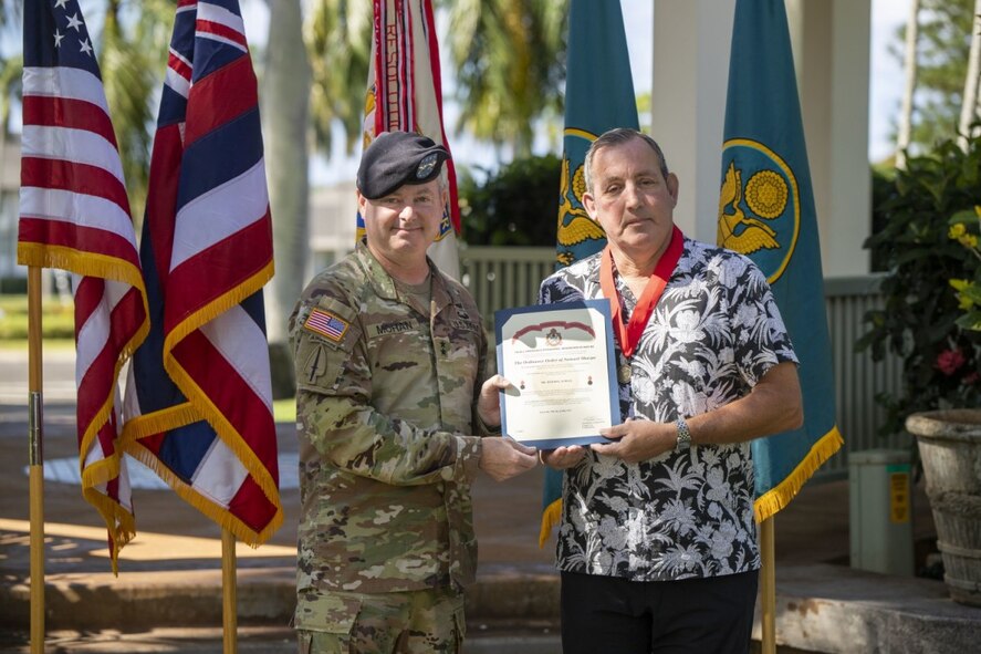 Army Sustainment Command commanding general, Maj. Gen. Chris Mohan, presents 402nd Army Field Support Brigade deputy to the commander, Joe Schulz, with the Ordinance Order of Samuel Sharpe.