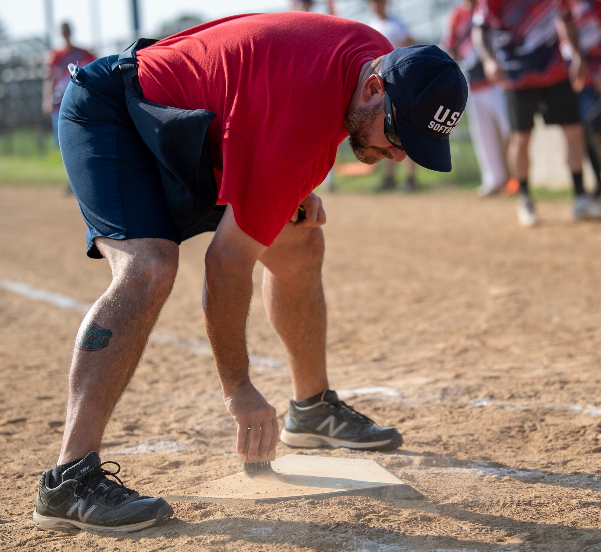 David Patch, volunteer umpire, cleans off home plate during an intramural softball game between the 436th Security Forces Squadron and the 436th Maintenance Squadron Isochronal Maintenance Dock on Dover Air Force Base, Delaware, July 26, 2021. The 436th SFS won the game 13-4. (U.S. Air Force photo by Tech. Sgt. Nicole Leidholm)