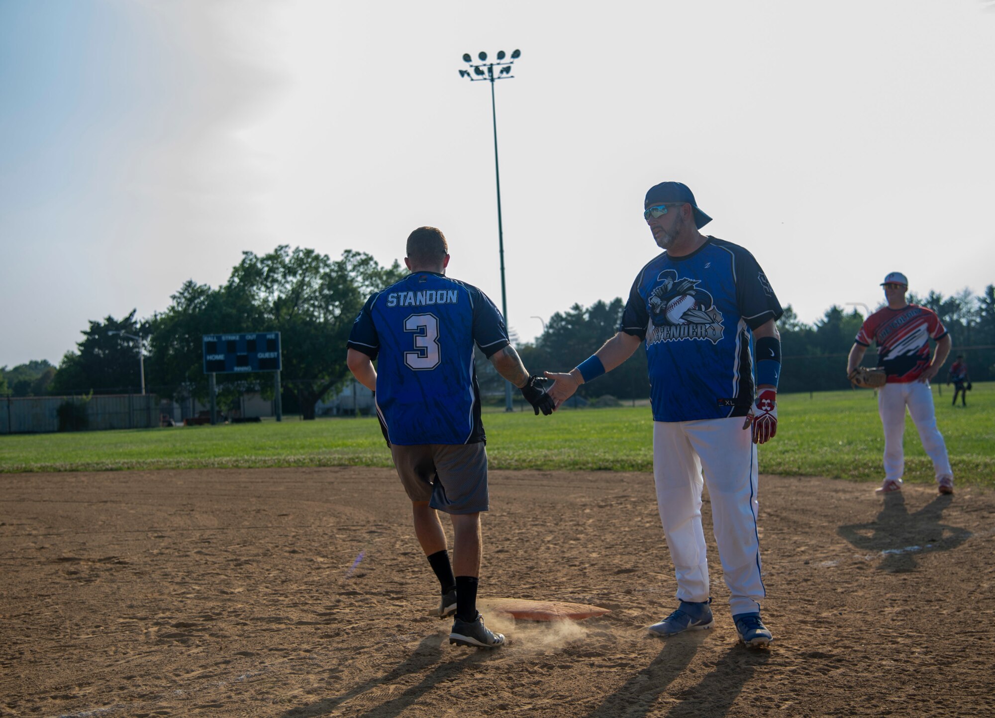 Richard Barker, right, 436th Security Forces Squadron security specialist, high fives Senior Airman Nicholas Standon, 436th SFS response force member, after reaching first base during an intramural softball game against the 436th Maintenance Squadron Isochronal Maintenance Dock on Dover Air Force Base, Delaware, July 26, 2021. The 436th SFS won the game 13-4. (U.S. Air Force photo by Tech. Sgt. Nicole Leidholm)
