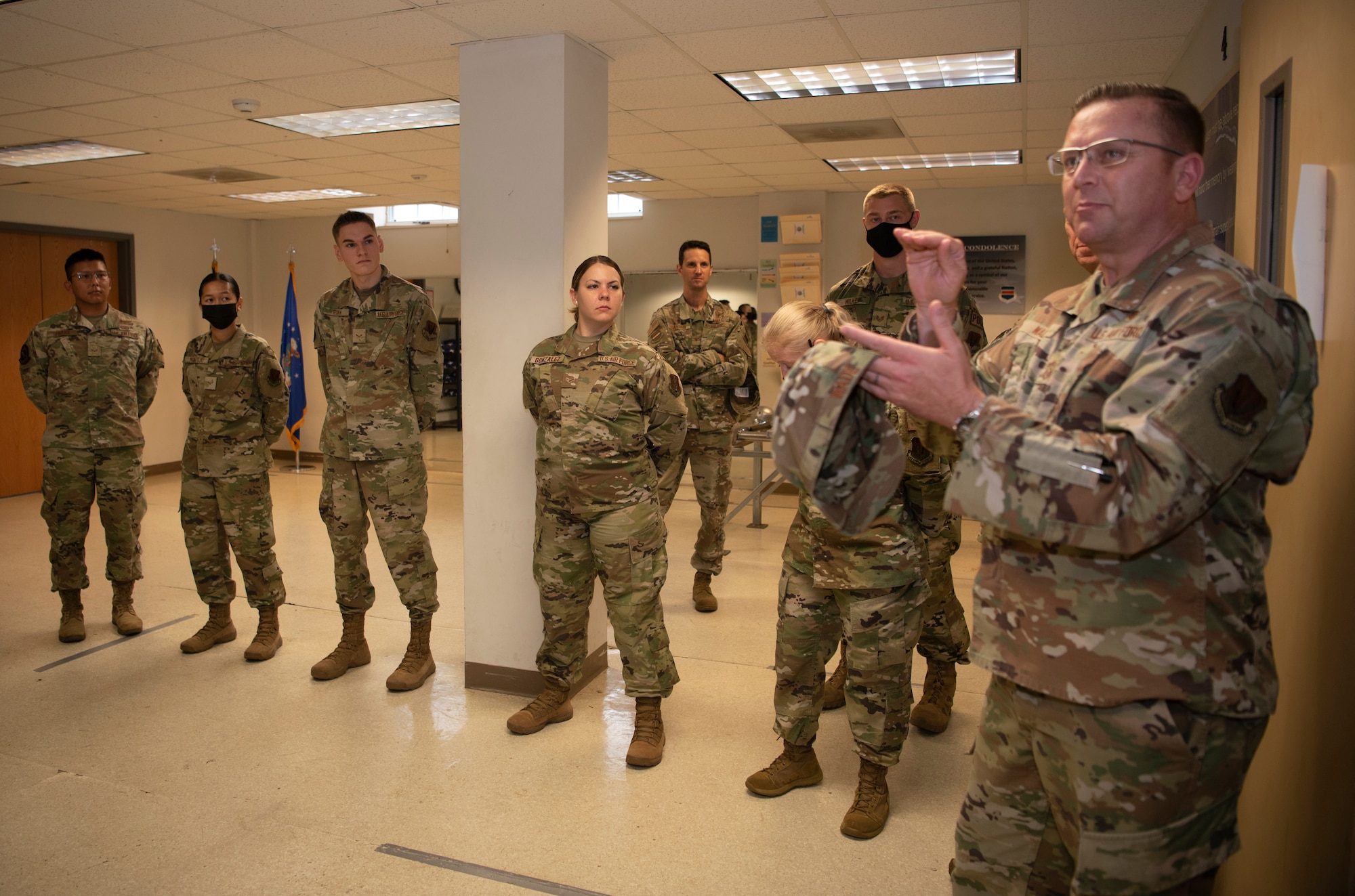 Command Chief Master Sgt. David Wade stands and talks with a group of Airmen in a room.
