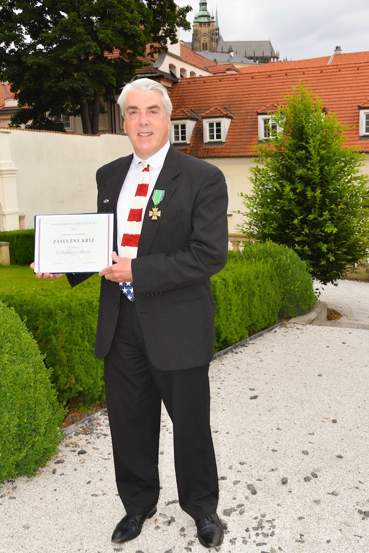 Dr. Stephen D. O’Regan stands with his newly awarded Cross of Merit citation in front of the United States Embassy in Prague, Czech Republic.