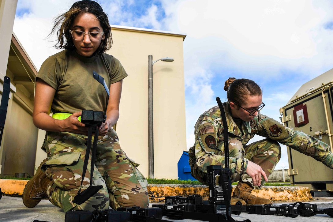 Two airmen check equipment on the ground.