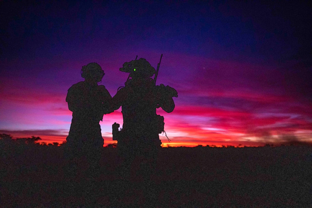 Two airmen shown in silhouette.