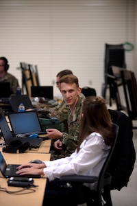 Sgt. Sean Singley, cyber threat intelligence analyst with the Oklahoma National Guard defensive cyber operations team, discusses recent cyber activity with Jenna Odgers, criminal intelligence analyst, Oklahoma State Bureau of Investigation, during Cyber Shield 2021 at the Armed Forces Reserve Center, Norman, Oklahoma, July 21, 2021. Cyber Shield is an annual training exercise focused on identifying and defending against cyber threats that compromise local and national security. (Oklahoma National Guard photo by Sgt. 1st Class Mireilie Merilice-Roberts)