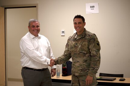 Capt. Danny Sluscharuk, Defense Cyber Operations Element chief with the Oklahoma National Guard defensive cyber operations team, shakes hands with Oklahoma State Bureau of Investigation Lt. Michael Dean, director of the OSBI Fusion Center, during Cyber Shield 2021 at the Norman Armed Forces Reserve Center, Norman, Oklahoma, July 21, 2021. Cyber Shield 21 focused on working in collaboration with state agencies to identify and defend against cyber threats that compromise local and national security. (Oklahoma National Guard photo by Sgt. 1st Class Mireilie Merilice-Roberts)