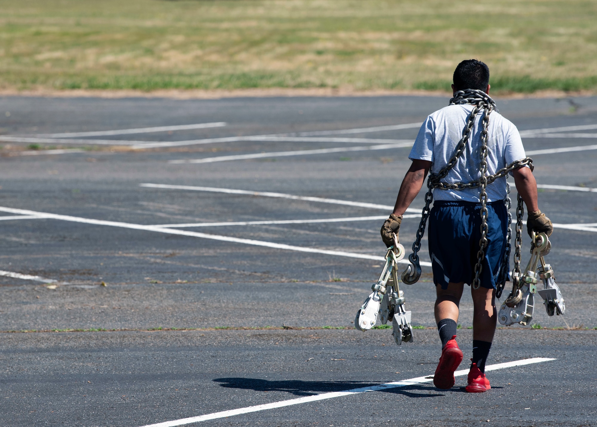 An Airman with the 62nd Aerial Port Squadron carries chains and other equipment across a course during a combat fitness challenge as part of the Eagle Port Rodeo Team tryouts at Joint Base Lewis-McChord, Washington, June 24, 2021. Once the team is chosen, they will travel to Joint Base Pearl Harbor-Hickam, Hawaii, to showcase their skills and build camaraderie with Port Dawgs from other wings. (U.S. Air Force photo by Senior Airman Zoe Thacker)