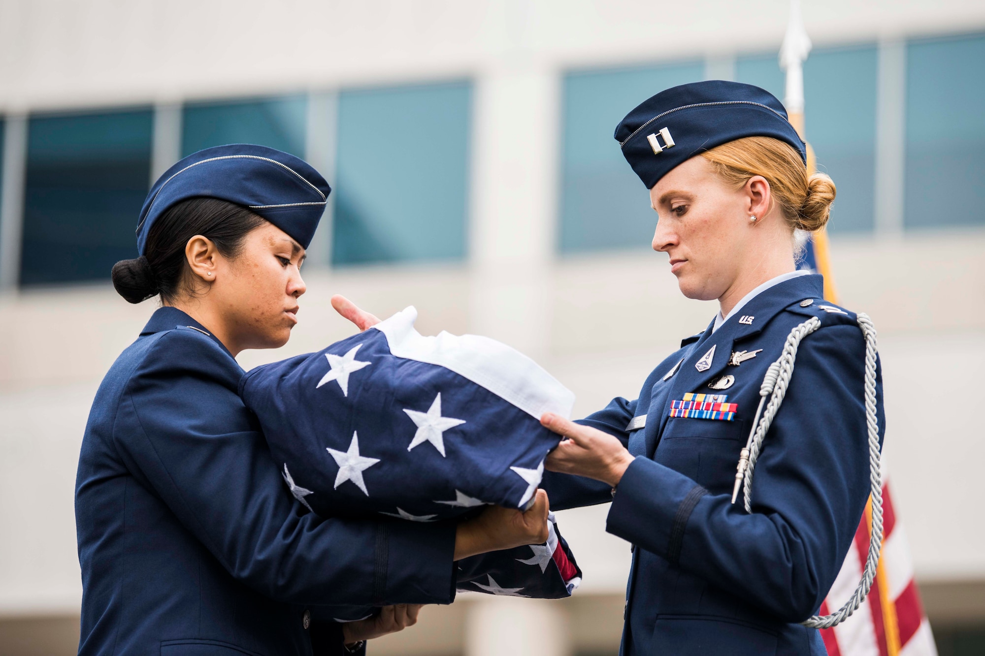 U.S. Space Force Captains Hannah Best and Kim Panagsagan, Space and Missile Systems Center officers, perform a ceremonial folding of the American flag during a retirement ceremony for U.S. Air Force Lt. Gen. John F. Thompson, SMC commander and Department of the Air Force Program Executive Officer for Space, at Los Angeles Air Force Base, California on July 27, 2021. Giving the flag a distinctive fold is a display of respect and gratitude to the individuals who fought, and continue to fight for freedom, at home and abroad. (U.S. Space Force photo by Staff Sgt. Luke Kitterman)