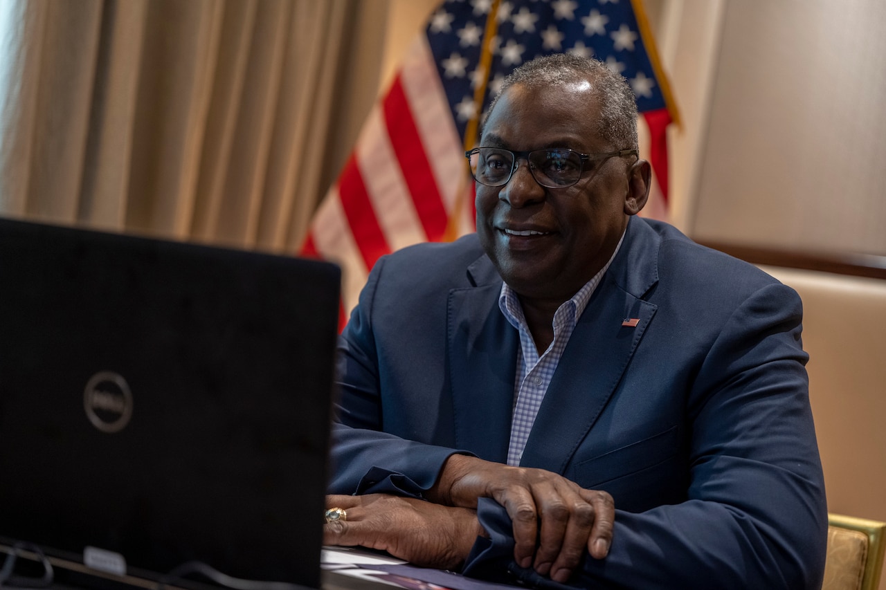 Secretary of Defense Lloyd J. Austin III sits at a desk and speaks with service members.