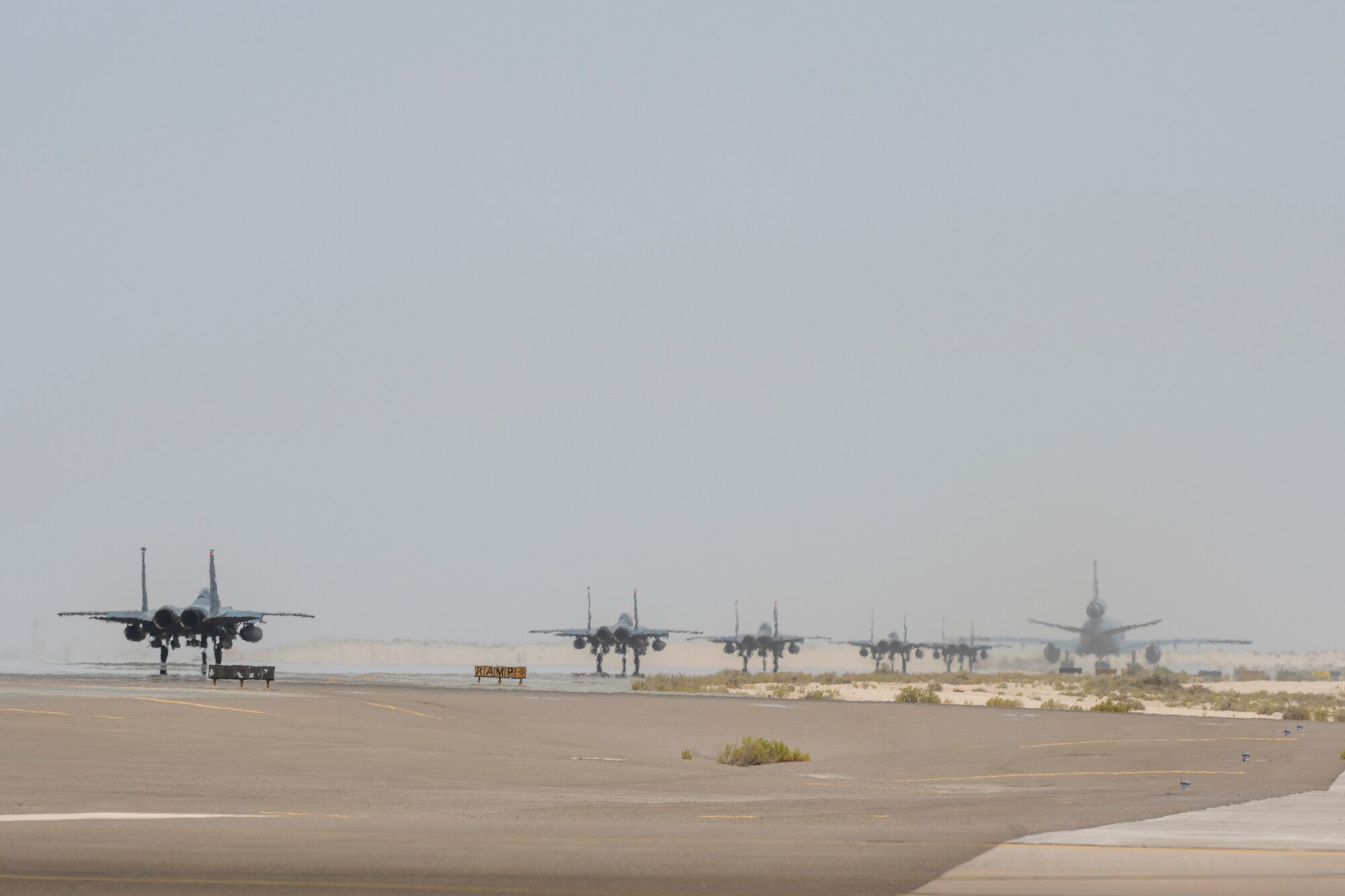 A KC-10 and 5 F-15s taxi down the runway