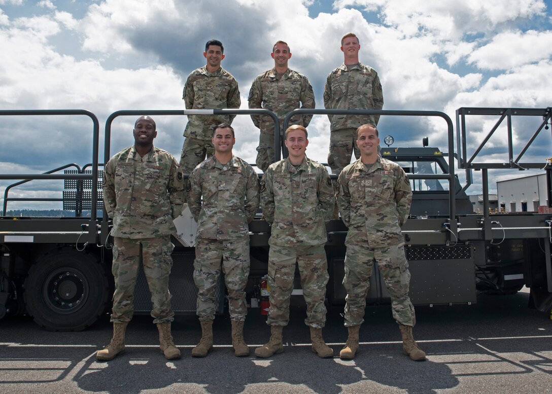 (From left, top to bottom) U.S. Air Force Tech. Sgt. Emmanuel Escobar, Senior Airman Connor Dickson, Senior Airman Hayden Floyd, Staff Sgt. Wesley Valentine, Tech. Sgt. Ronald West, Senior Airman Trenton Dancer and Airman 1st Class Clay Huddleston, all members of the 62nd Aerial Port Squadron, pose for a photo at Joint Base Lewis-McChord, Washington, July 21, 2021. They make up the team of aerial port Airmen that will travel to Joint Base Pearl Harbor-Hickam, Hawaii, in August to compete in the 2021 Pacific Air Forces (PACAF) Port Dawg Rodeo. (U.S. Air Force photo by Senior Airman Zoe Thacker)