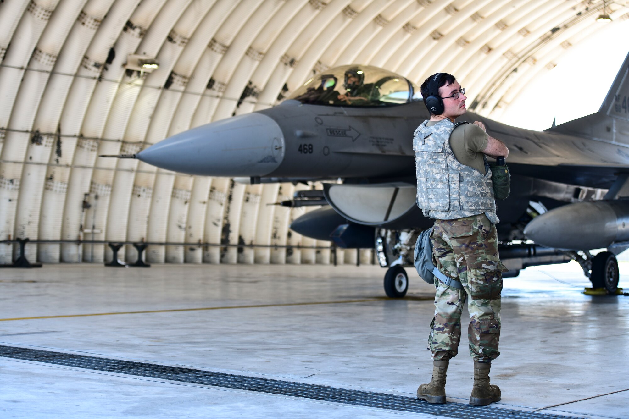 A maintainer prepares to marshal a jet.