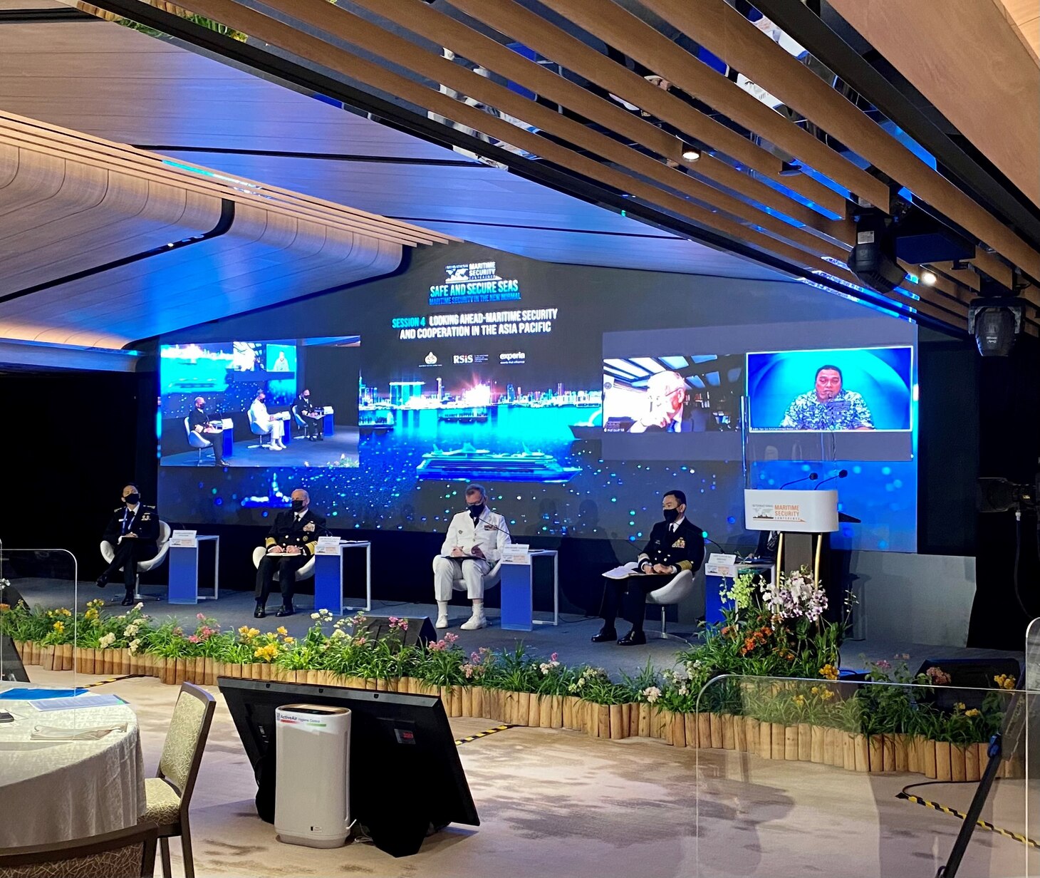 Four men sit on a stage at a conference.