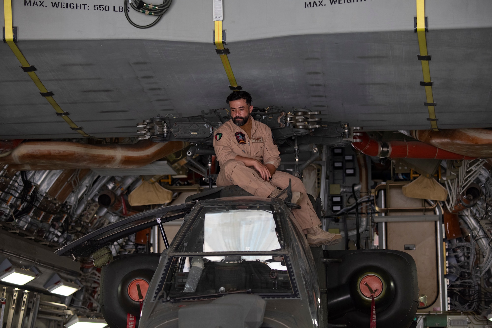 A member of the Kuwait Air Force sits on top of an AH-64E APACHE inside of a Kuwait Air Force C-17 Globemaster III at Ali Al Salem Air Base, Kuwait, July 26, 2021. One of the priorities of the 386th Air Expeditionary Wing is to foster enduring partnerships. These partnerships are built on mutual respect and critical to current and future missions. (U.S. Air Force Senior Airman Helena Owens)