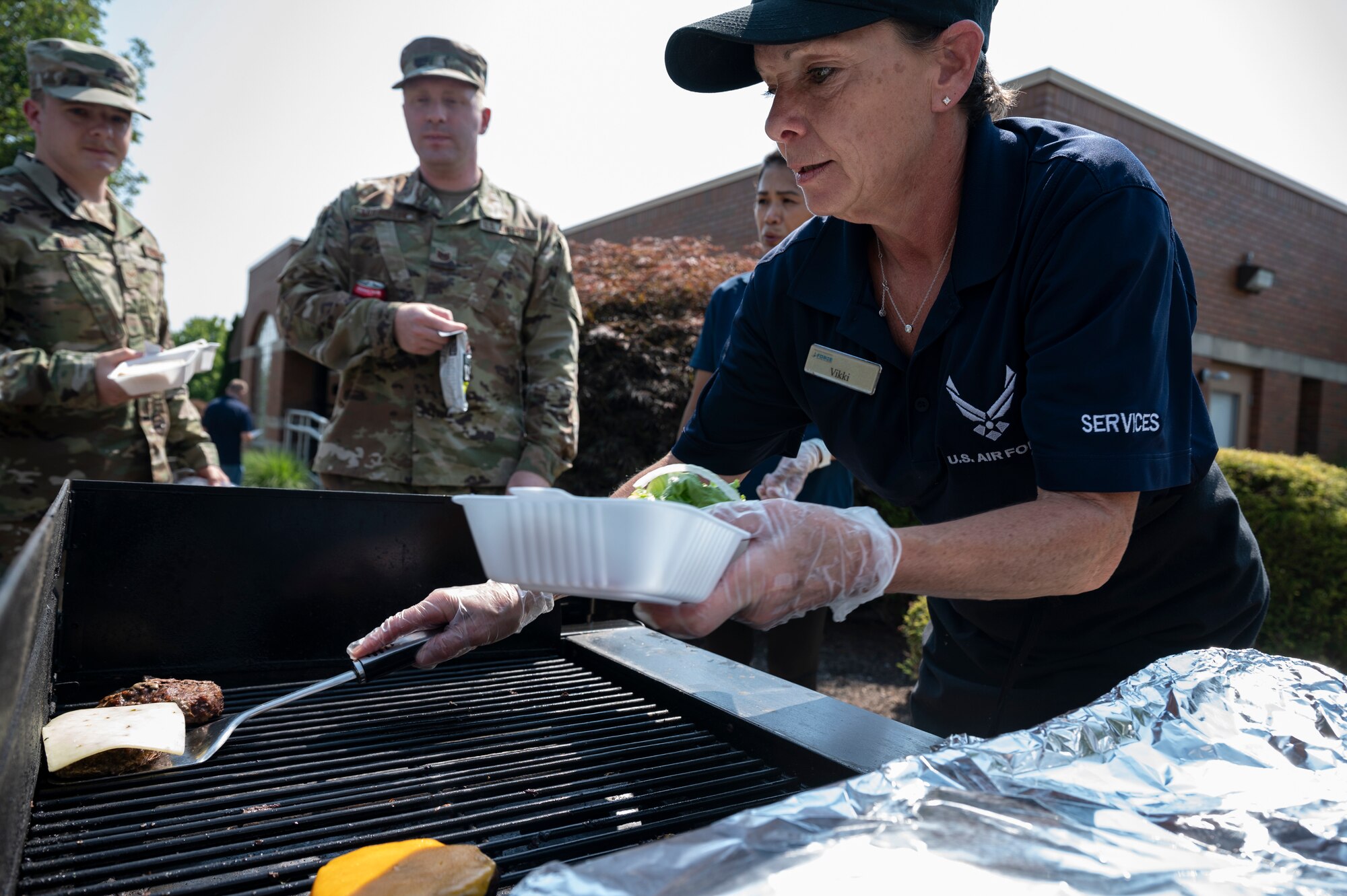 Vikki Richards, 911th Force Support Squadron cook, serves Airmen burgers during a burger burn at the Pittsburgh International Airport Air Reserve Station, Pennsylvania, July 27, 2021. The 911th FSS held the burger burn to thank Air Force Club members while trying to increase membership.