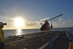 Crewmembers from the Coast Guard Cutter Harriet Lane conduct sunset flight operations with an MH-65 Dolphin aircrew from Coast Guard Air Station Miami in the Caribbean Sea.