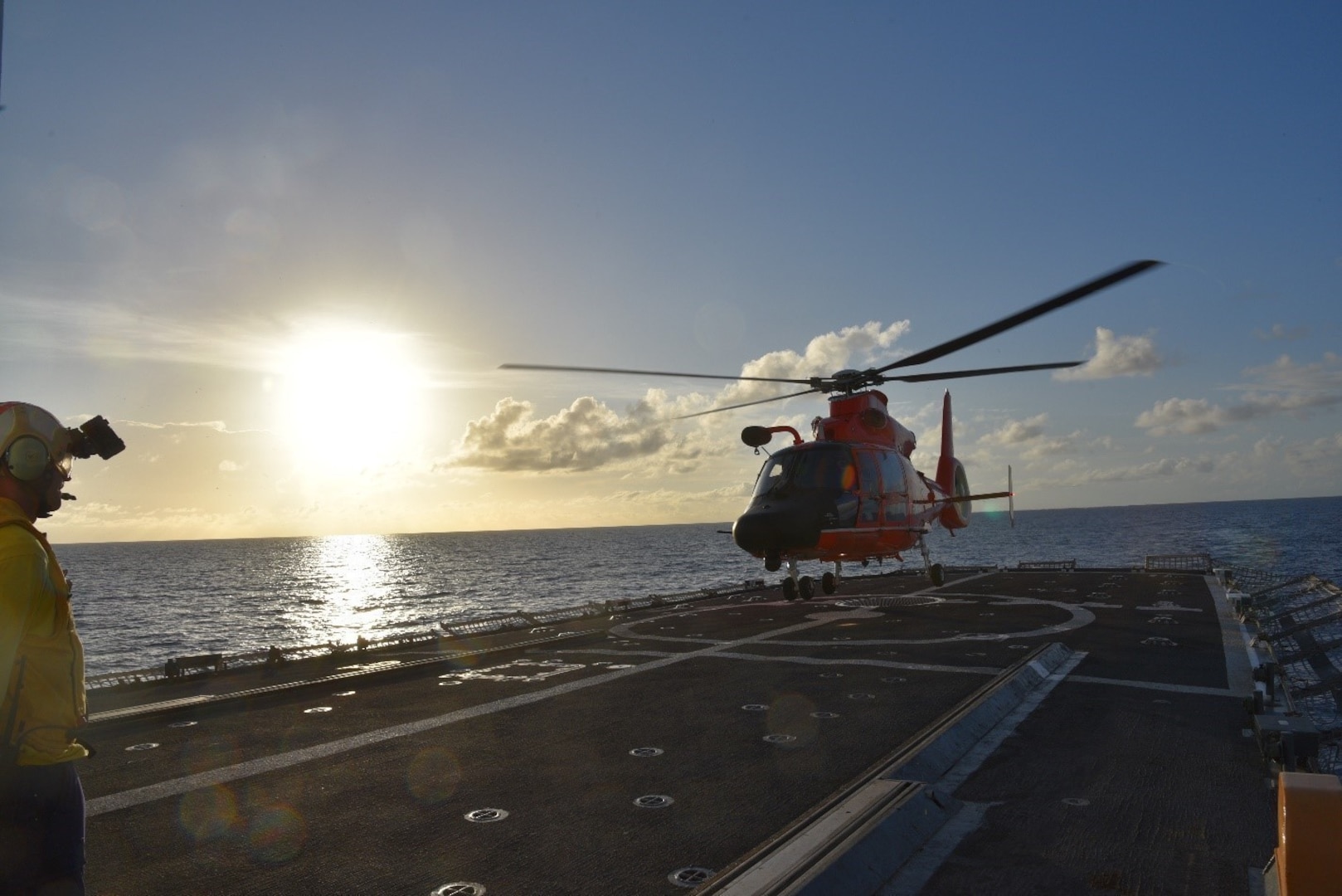 Crewmembers from the Coast Guard Cutter Harriet Lane conduct sunset flight operations with an MH-65 Dolphin aircrew from Coast Guard Air Station Miami in the Caribbean Sea.
