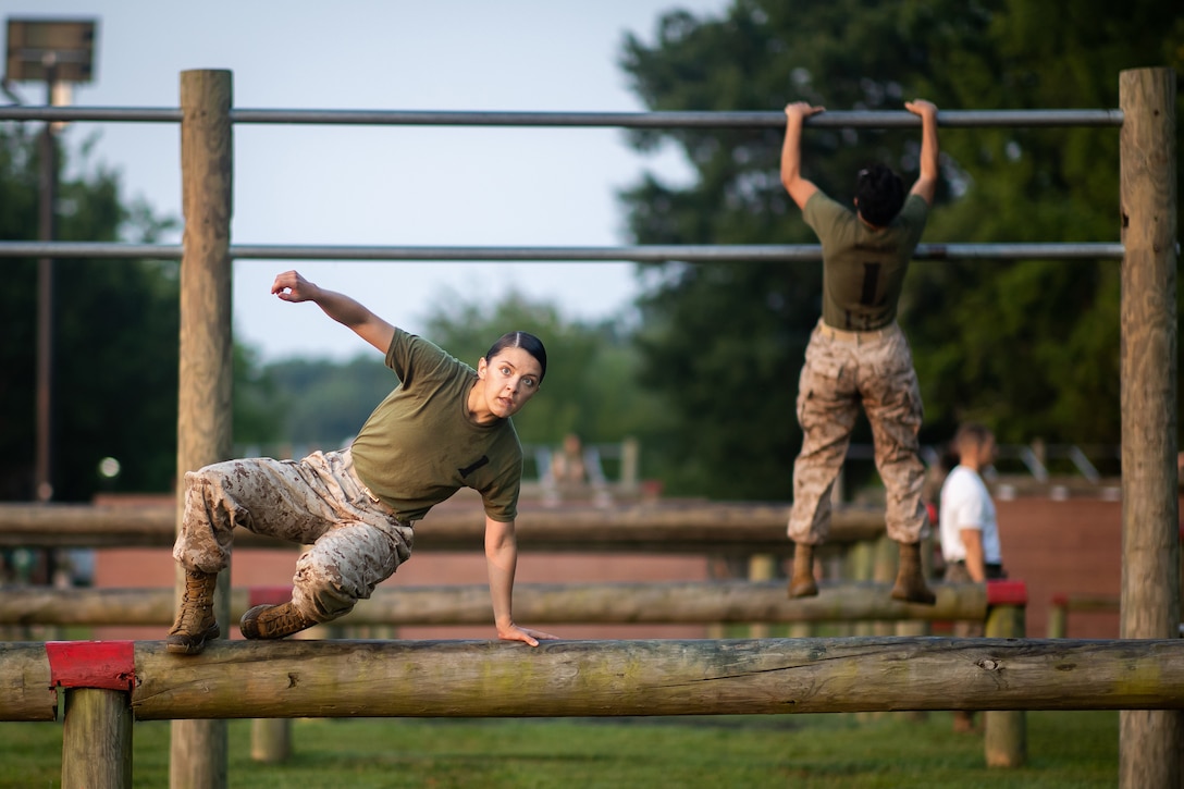 A Marine hurdles over a log on an obstacle course.