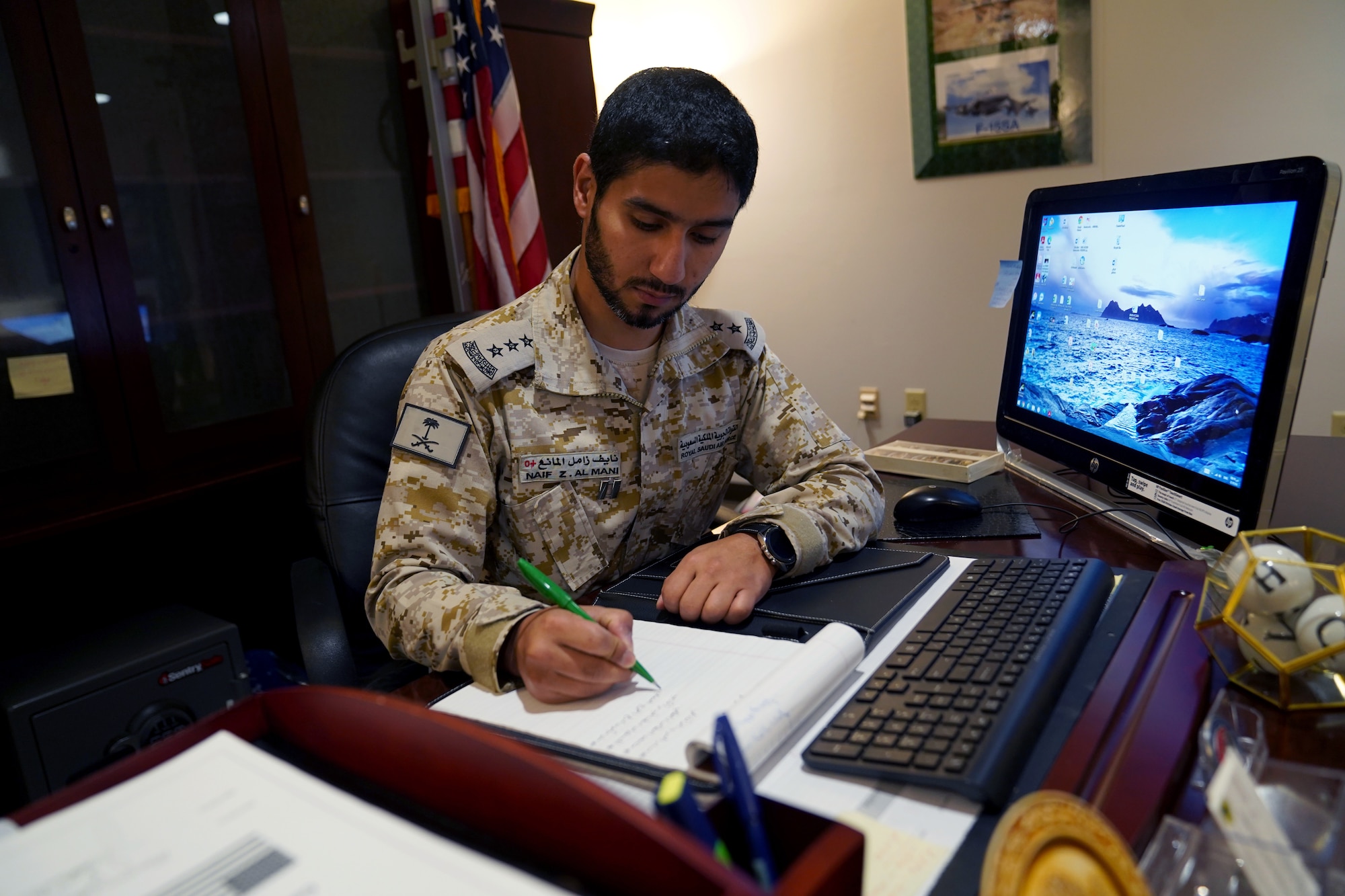 Royal Saudi air force Capt. Naif Almani, Keesler Saudi country liaison officer, performs his work duties at his desk inside the Volser Academic Development Center at Keesler Air Force Base, Mississippi, July 28, 2021. Almani provided his support for the local community by translating exams for a student in the Harrison County School District. (U.S. Air Force photo by Senior Airman Seth Haddix)