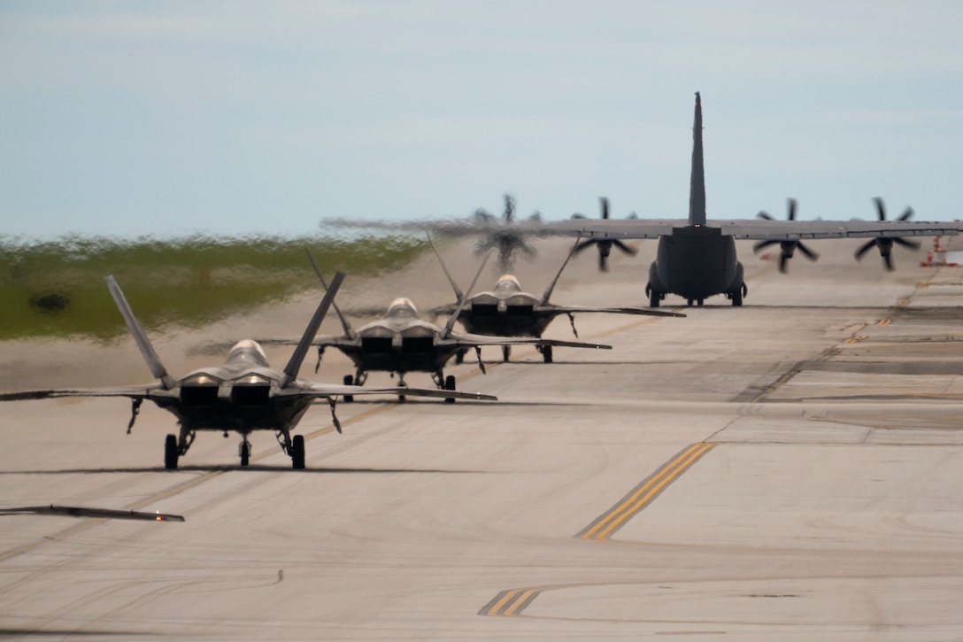 Aircraft sit in line on a runway before takeoff.