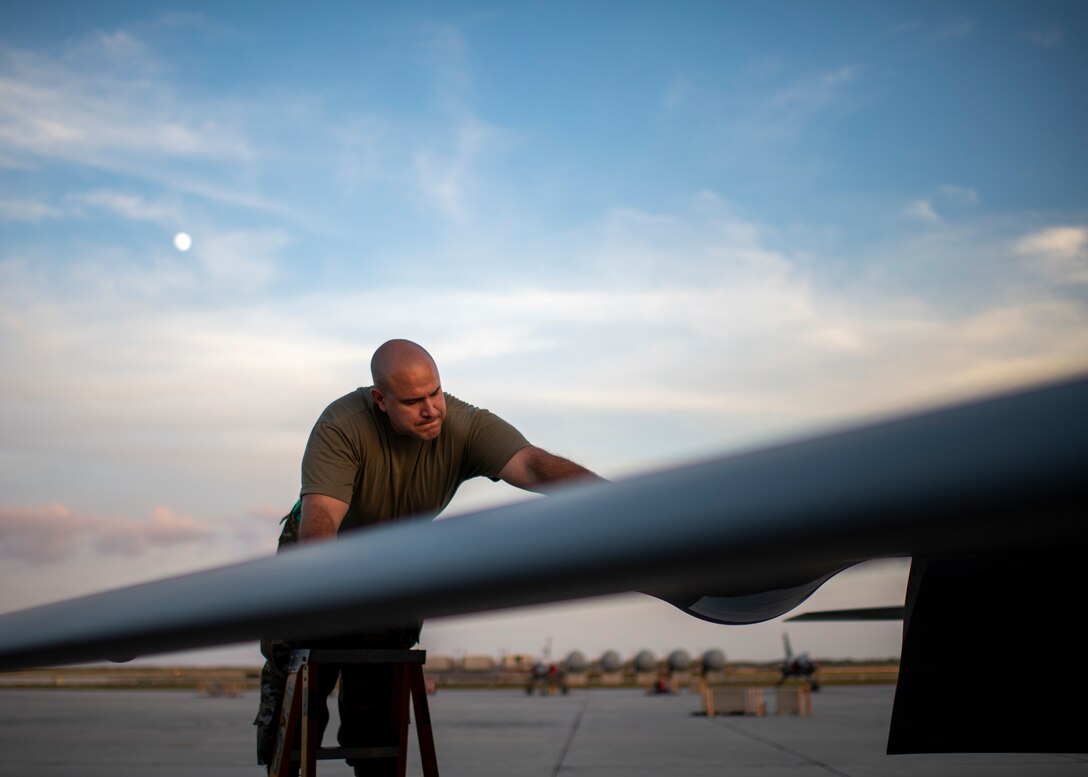 A man stands on a ladder near the wing of a plane