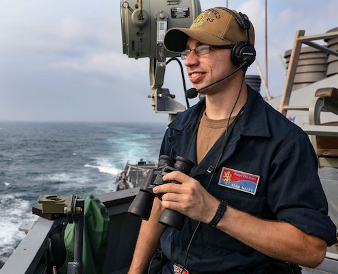 Seaman Adam Maley, from Windham, Maine, stands lookout watch on the starboard bridge wing of the Arleigh Burke-class guided-missile destroyer USS Benfold (DDG 65) as the ship transits the Taiwan Strait.