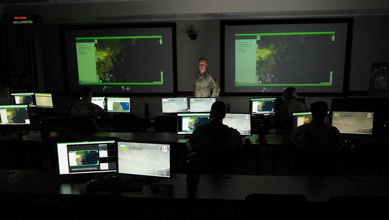 People work on laptops in a dark room.