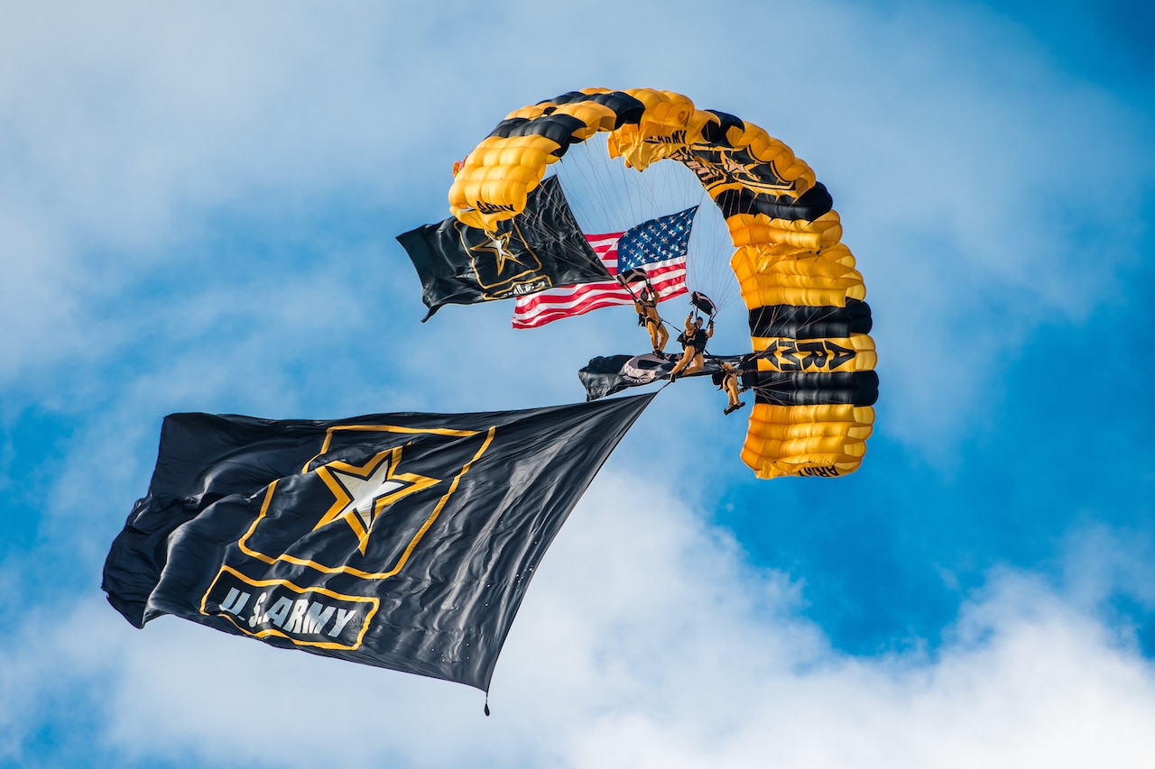 A soldier freefalls with a parachute carrying the American flag.