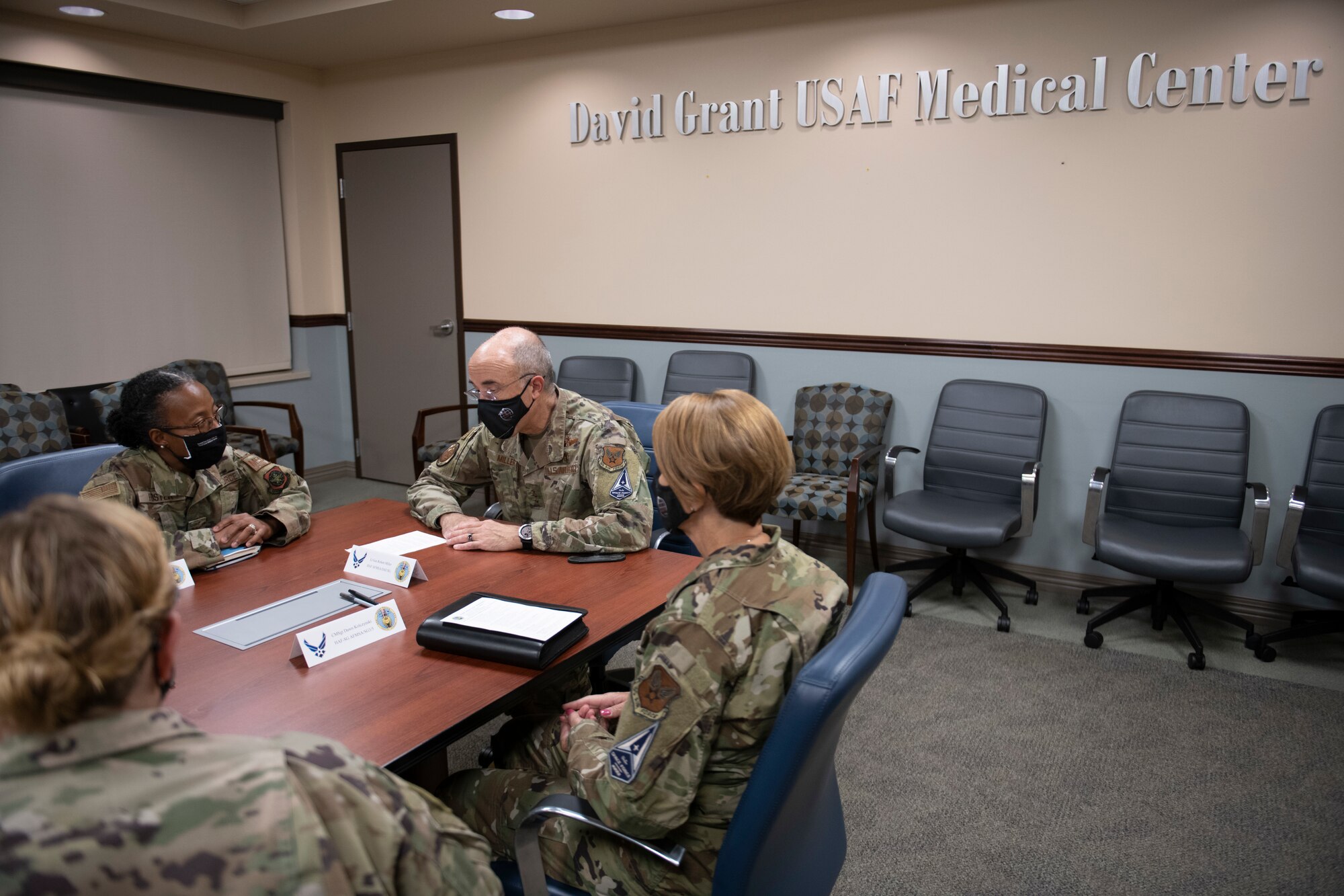 U.S. Air Force Lt. Gen. Robert Miller, Air Force and Space Force Surgeon General, second from right, sit at a conference style table with Col. Gwendolyn Foster, 60th Medical Group commander, second from left, at Travis Air Force Base, California, July 27, 2021.
