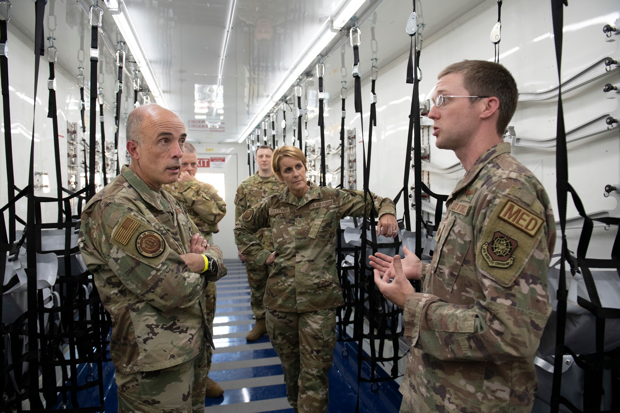 U.S. Air Force Major Michael Broome, 775th Expeditionary Aeromedical Evacuation Flight infectious disease nurse, right, briefs Lt. Gen. Robert Miller, Air Force and Space Force Surgeon General, left, and Chief Master Sgt. Dawn Kolczynski, medical enlisted force and enlisted corps chief, center, inside a Negatively Pressurized Connex July 27, 2021, at Travis Air Force Base, California.
