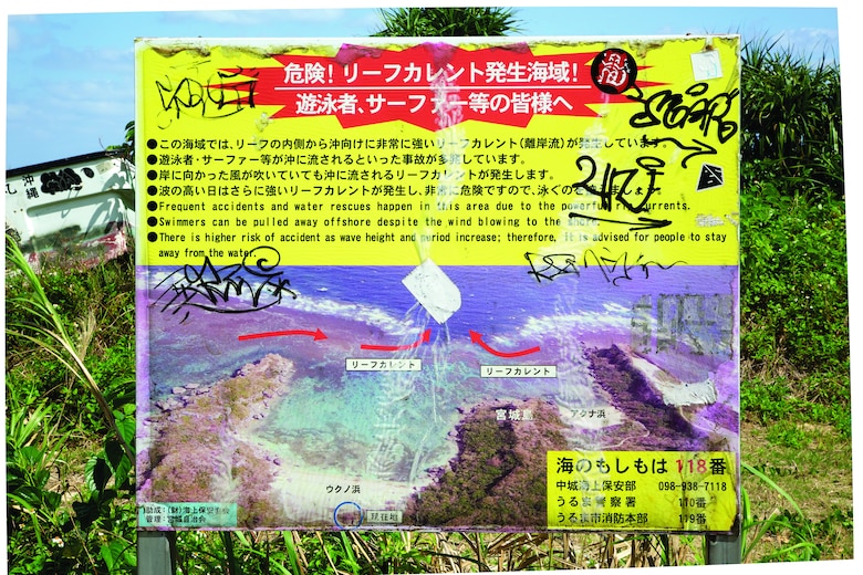 A sign on a remote beach warns of the dangers in the area. Signs are made by the land owners accordingly with Okinawa Prefecture Outdoor Advertisement Ordinance.