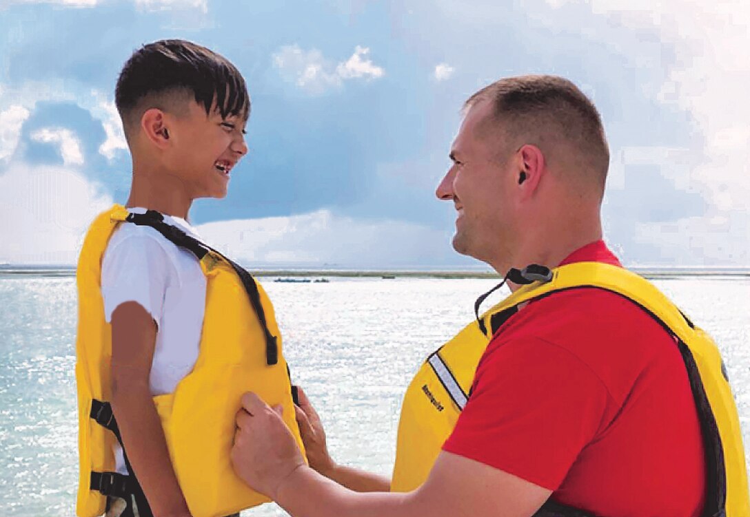 A father puts a life jacket on his son.